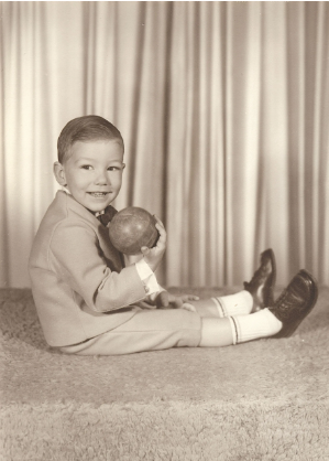 Mike as a young child sitting with a ball, vintage school portrait