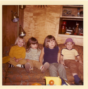 Mike as a child sitting on a couch with siblings, vintage family photo