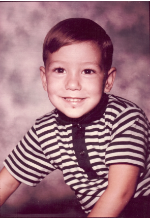 Mike as a young boy in a striped shirt, school portrait
